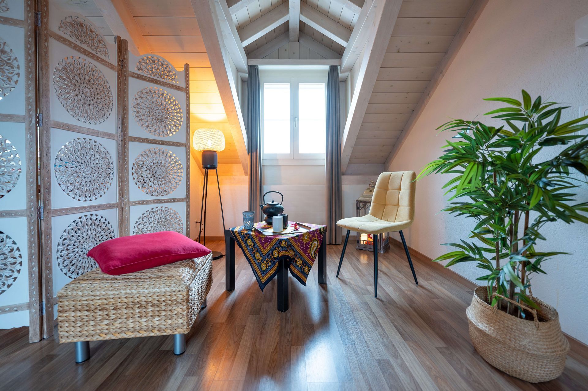 Ein gemütliches Wohnzimmer mit einem Tisch, Stühlen, einer Pflanze und einem Paravent.