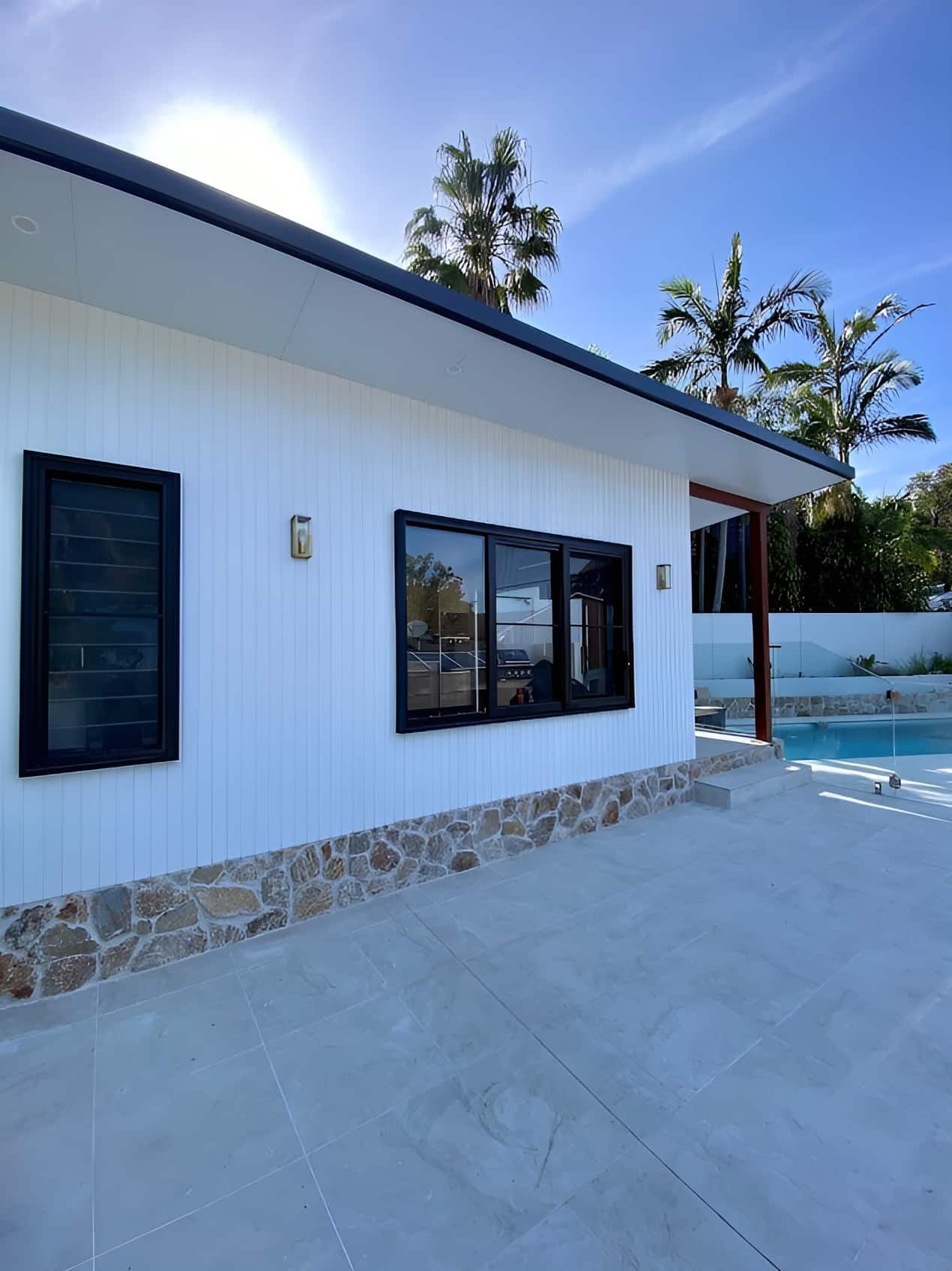 A White House With Black Windows And A Swimming Pool In The Background — Designer Building Pty Ltd In Charmhaven, NSW