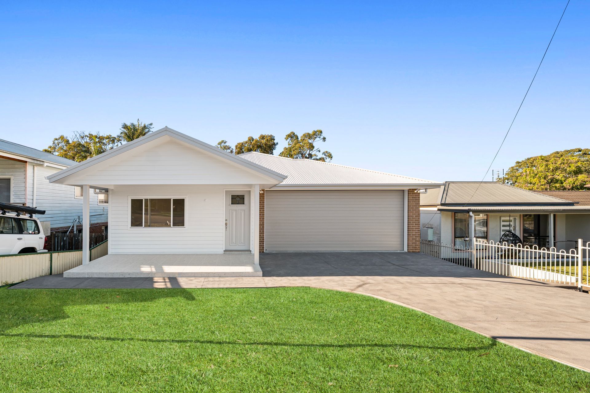 White House with Garage, Driveway, and Lawn on A Sunny Day — Designer Building Pty Ltd In Charmhaven, NSW
