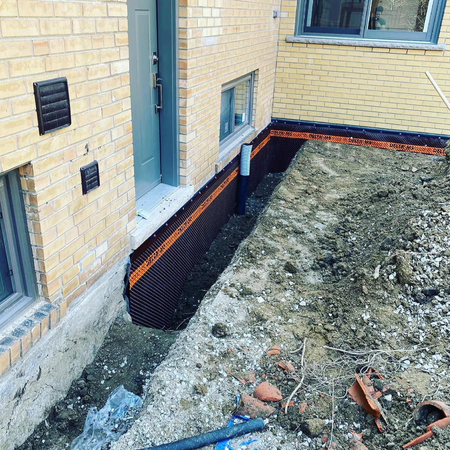 A brick building with a hole in the ground in front of it.