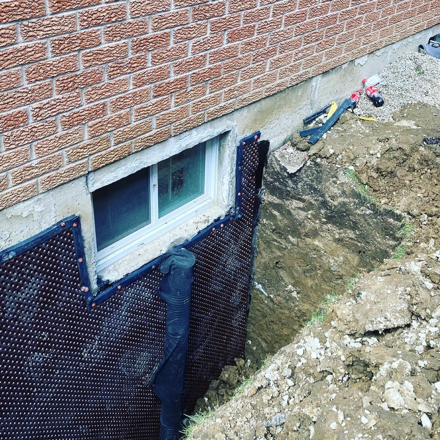 A brick wall with a window and a hole in the ground.
