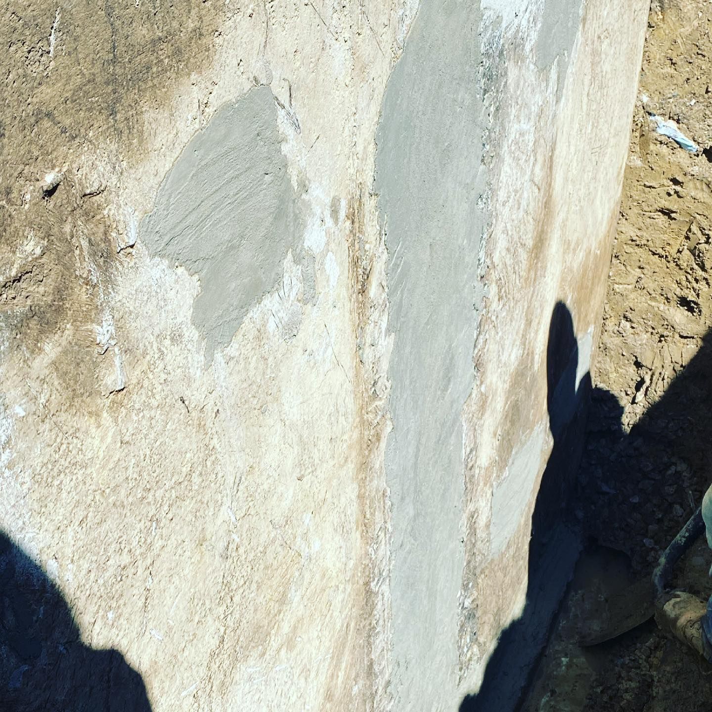 A shadow of a person is cast on a concrete wall