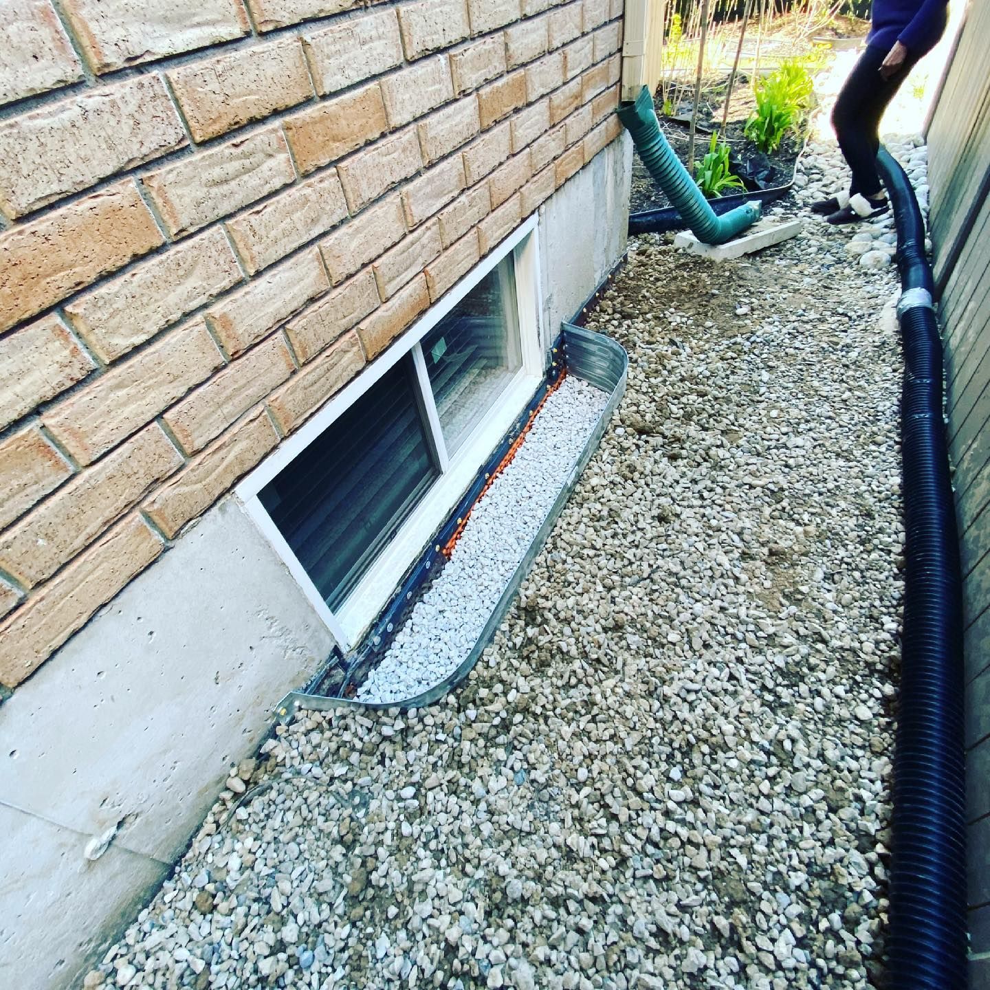 A person is standing next to a brick wall with a window in it.
