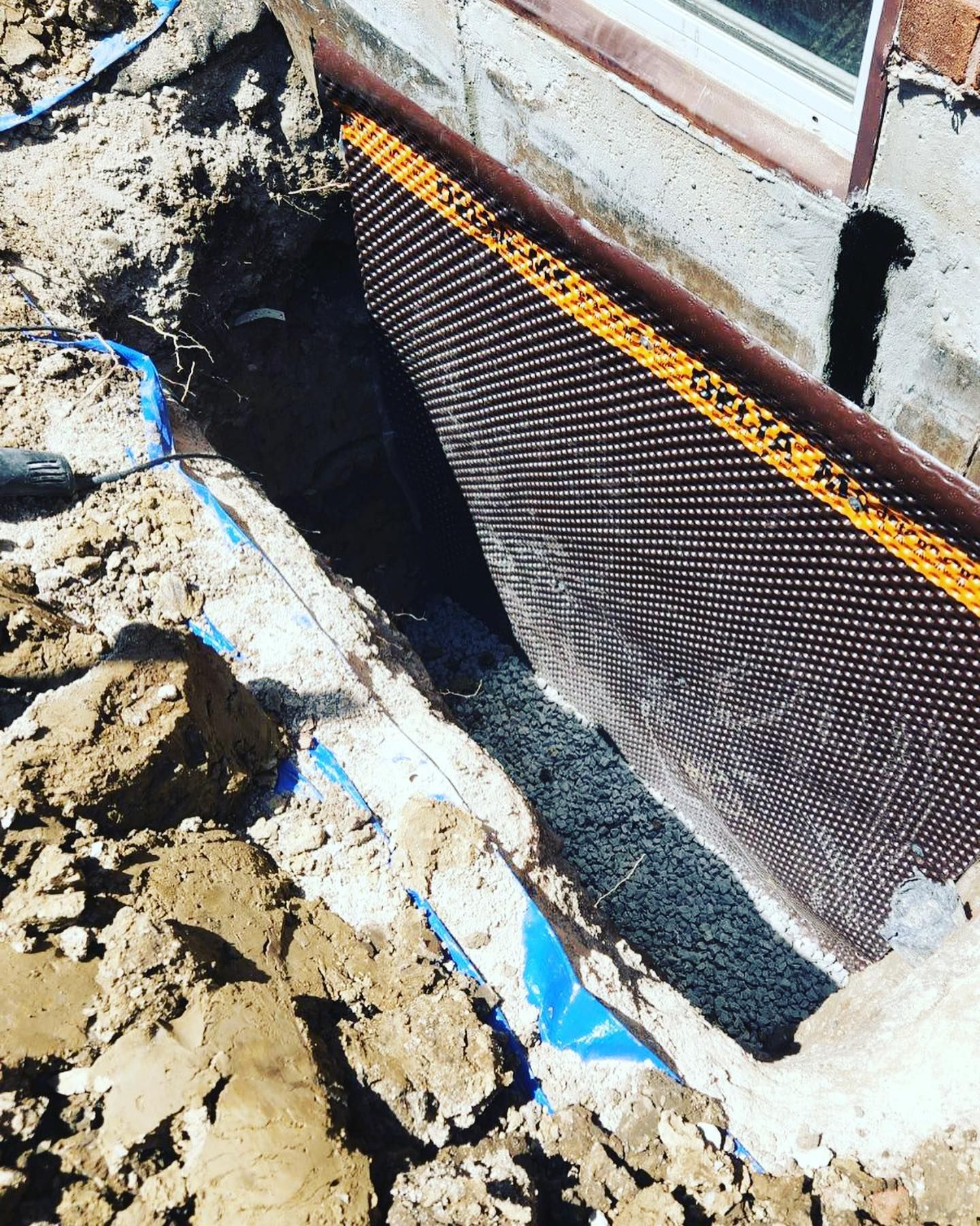 A drainage system is being installed on the side of a building.