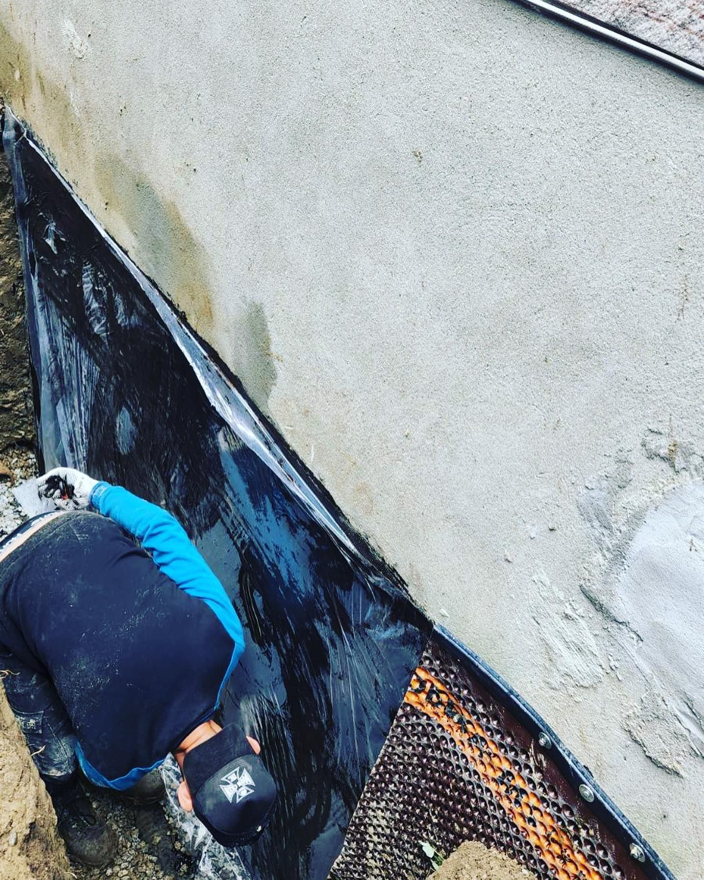 A man wearing a helmet is working on a concrete wall