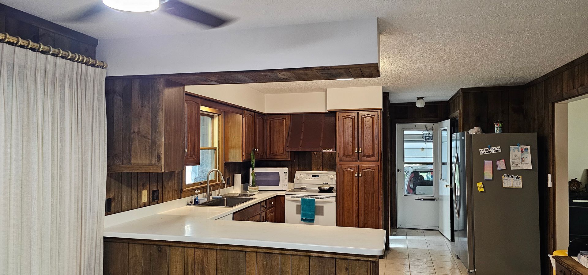 Bright kitchen with cherry wood cabinets, granite island, stainless steel fridge, and two pendant lights.