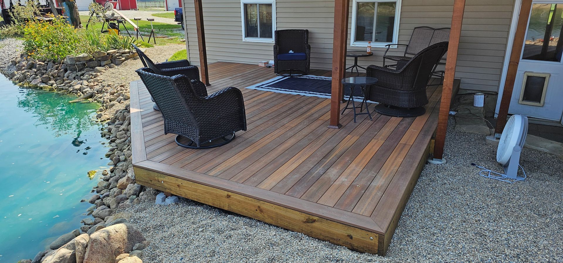 Wooden deck overlooking a calm lake, with trees and a cloudy sky in the background