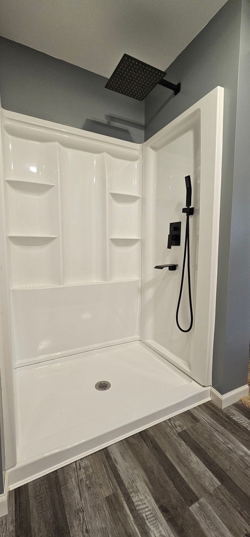 Bright white bathroom with a freestanding tub, subway tile, glass shower, and window with blinds.