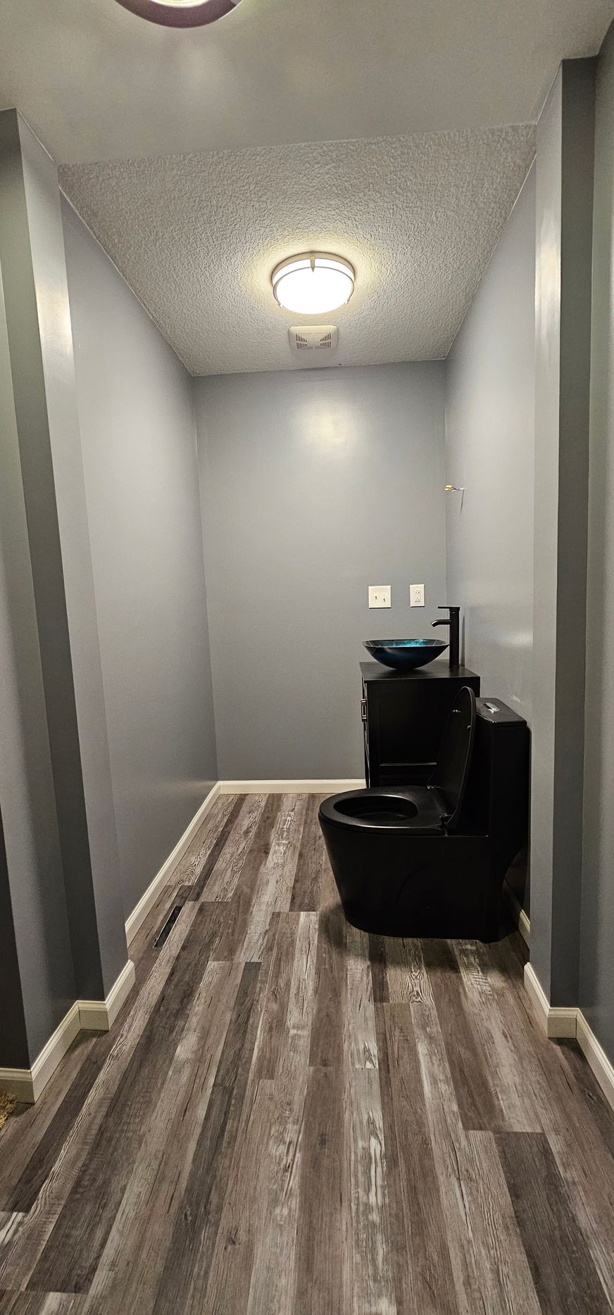 White tiled bathtub and shower with blue accent strip and black fixtures in a modern bathroom