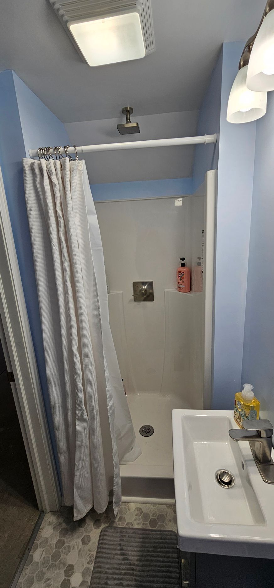 White tiled bathtub and shower with blue accent strip and black fixtures in a modern bathroom