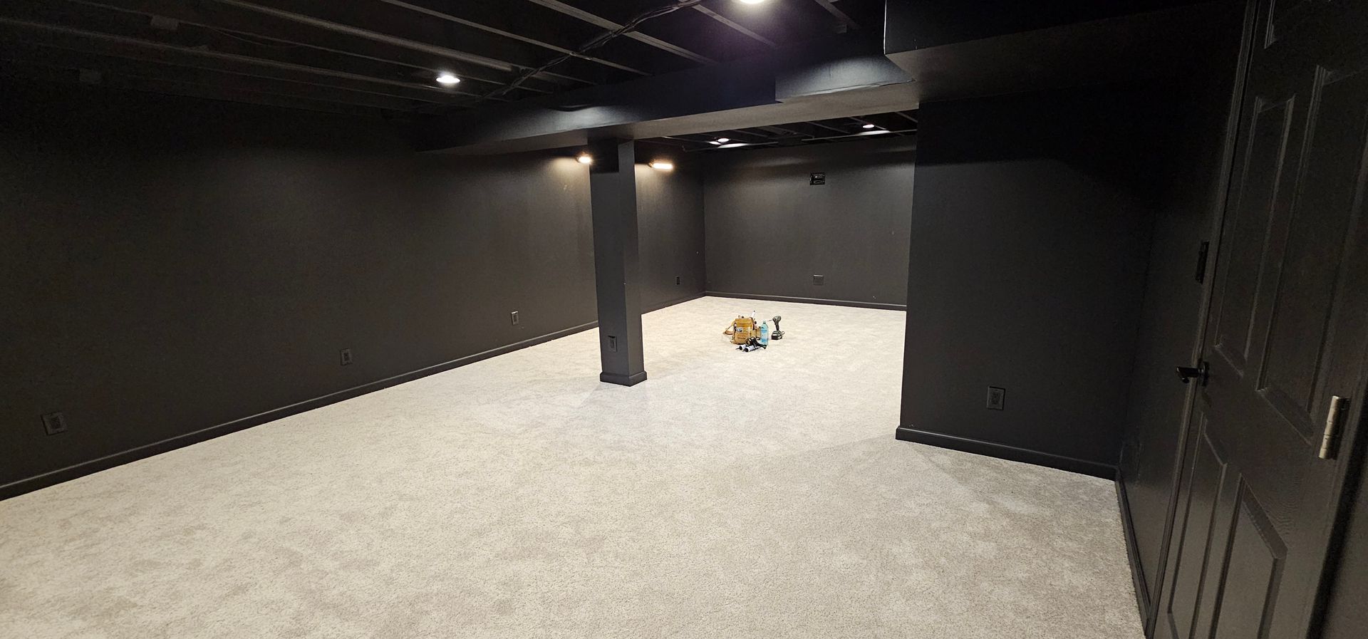 Empty finished basement with carpet, gray walls, recessed lights, and stairs on the right