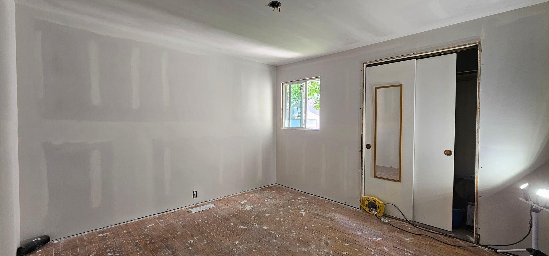 Empty white interior hallway under renovation with open doorways and unfinished walls