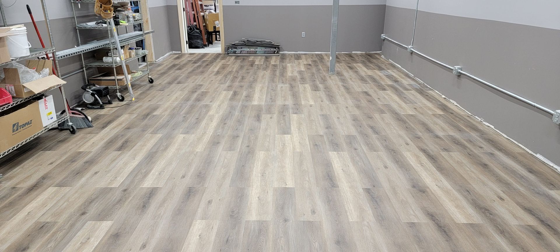 Bright empty room with dark wood floors, white walls, large bay window, and built-in shelving