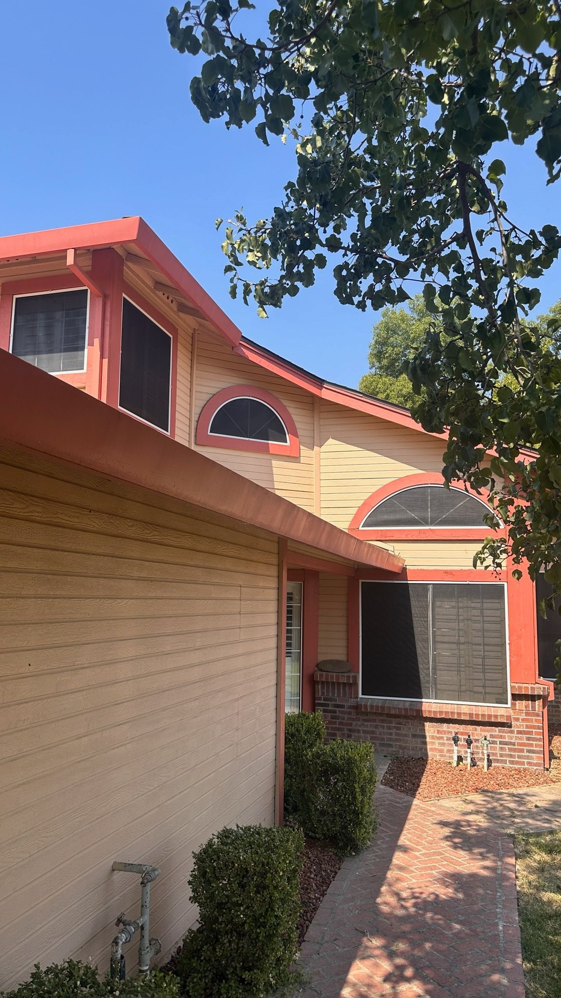 A house with a red roof and a brick walkway leading to it.