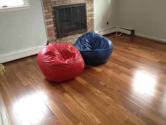 Two bean bag chairs are sitting on a wooden floor in front of a fireplace.