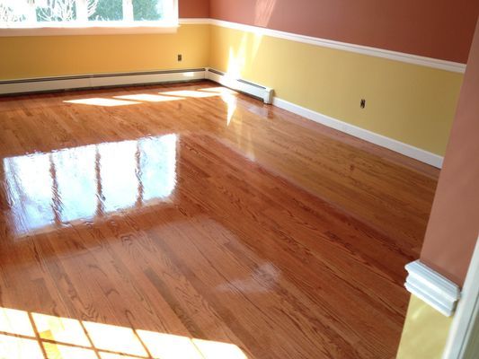 A wooden floor in front of a brick fireplace.