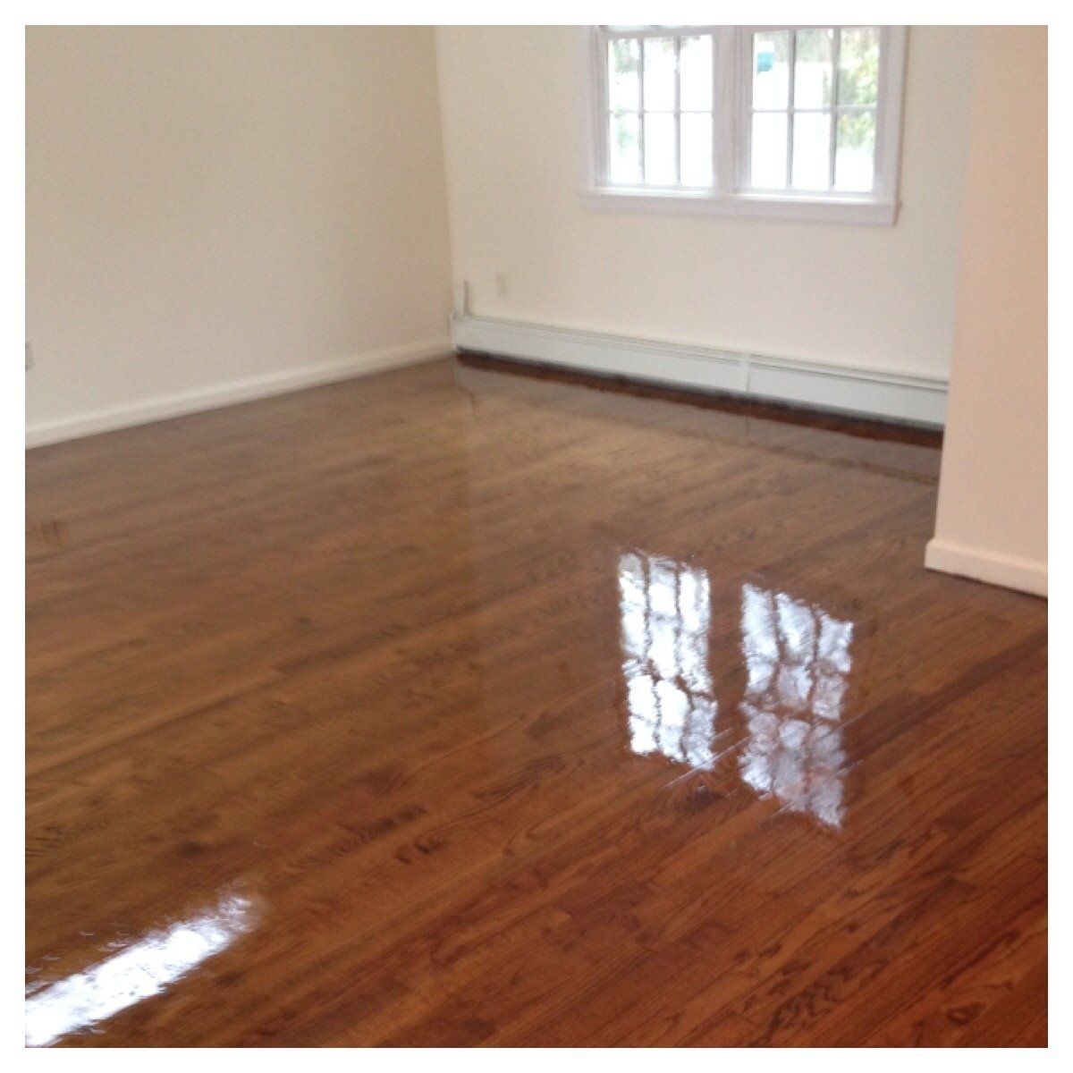 An empty room with hardwood floors and a window