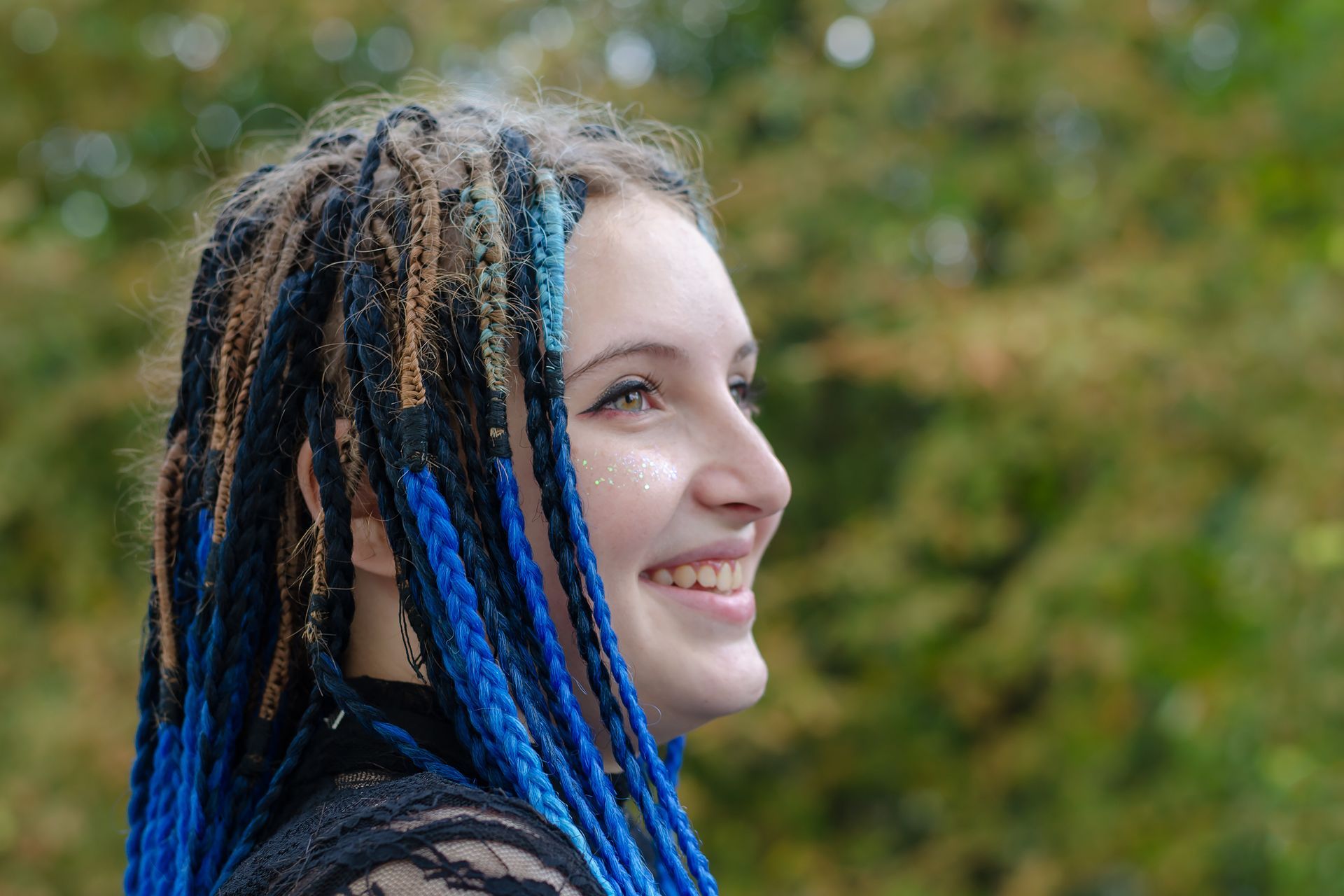 a woman with blue dreadlocks is smiling and looking to the side