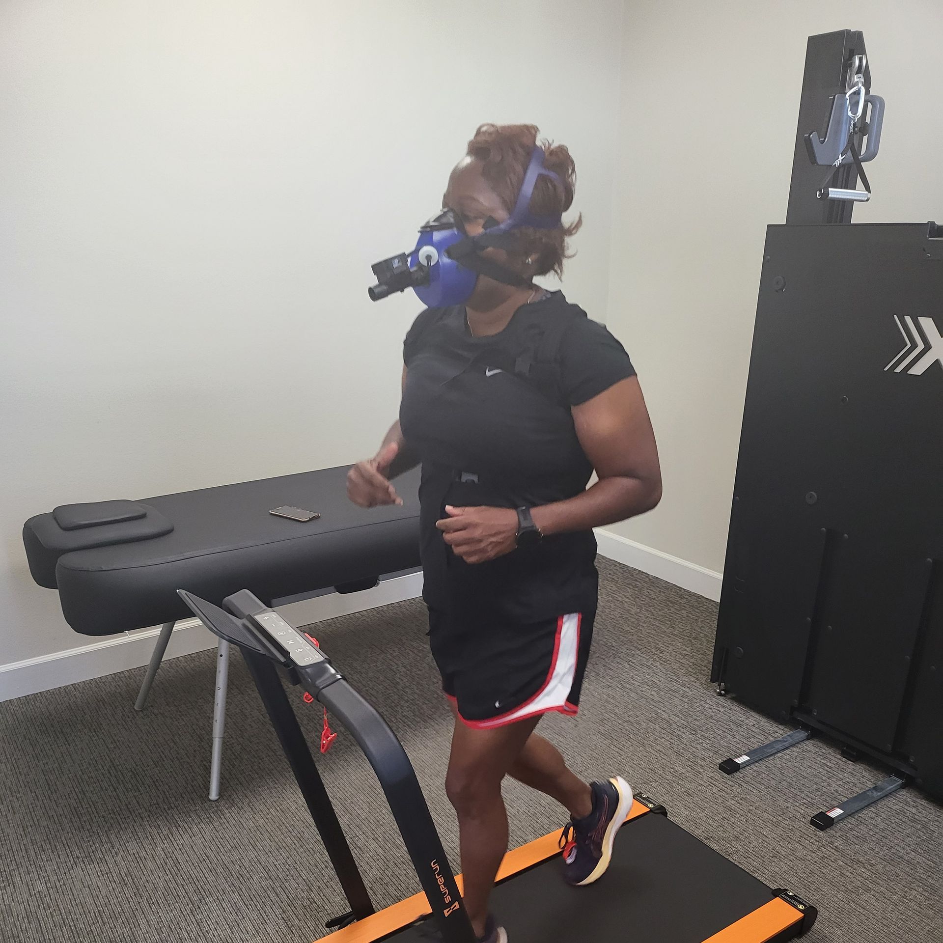 A woman running on a treadmill while equipped with the PNOE device, highlighting the role of VO2 Max score in Motivation and Goal Setting. Clients can track their fitness journey, set achievable goals, and witness concrete improvements in cardiovascular health, which serves as a powerful motivator for maintaining an active lifestyle.
