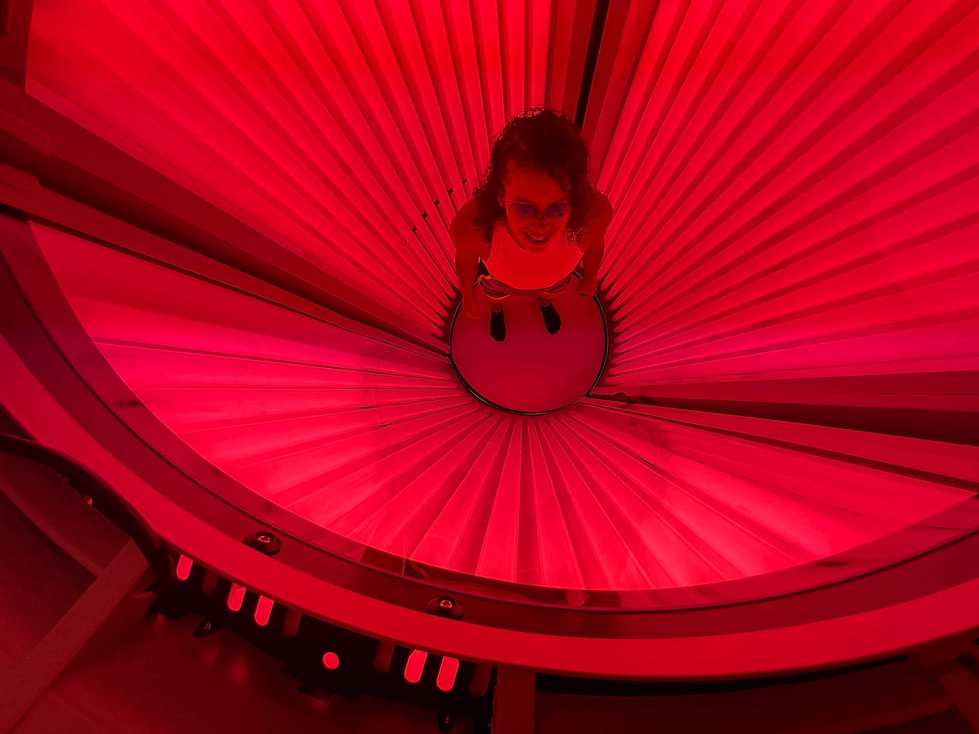 A woman inside a Red Light Therapy chamber, benefiting from Mood and Sleep Enhancement as the therapy influences the body's circadian rhythm, potentially increasing serotonin production. This can lead to an improved mood and better sleep quality, contributing to a more balanced and contented life.