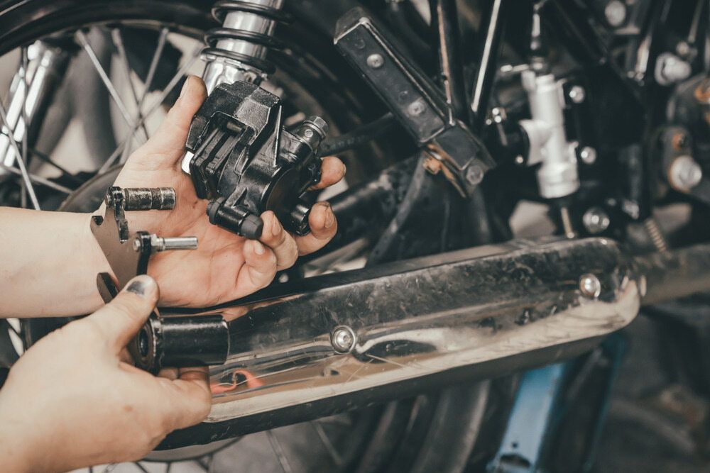 Hands Working on Motorcycle Brakes — Resurge Diesel & Fabrication Pty Ltd In Balnagowan, QLD