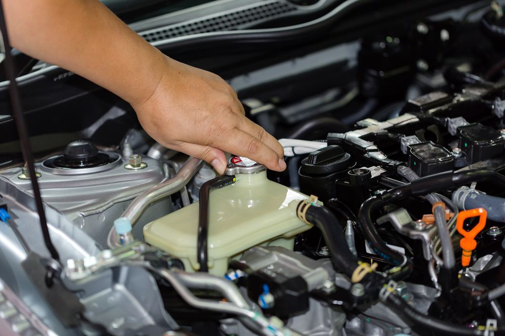 Hand Opening a Car Coolant Reservoir in an Engine Bay — Resurge Diesel & Fabrication Pty Ltd In Balnagowan, QLD