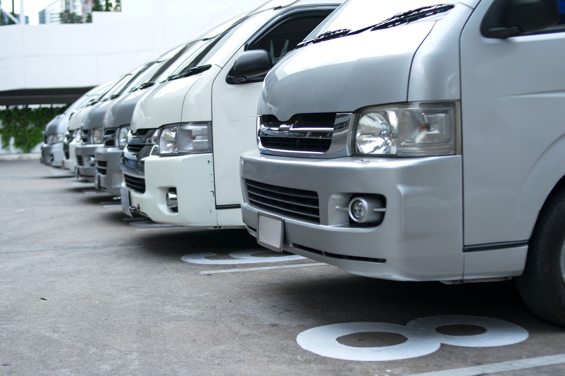 Row Of White Vans Parked In Numbered Parking Spaces — Resurge Diesel & Fabrication Pty Ltd In Balnagowan, QLD