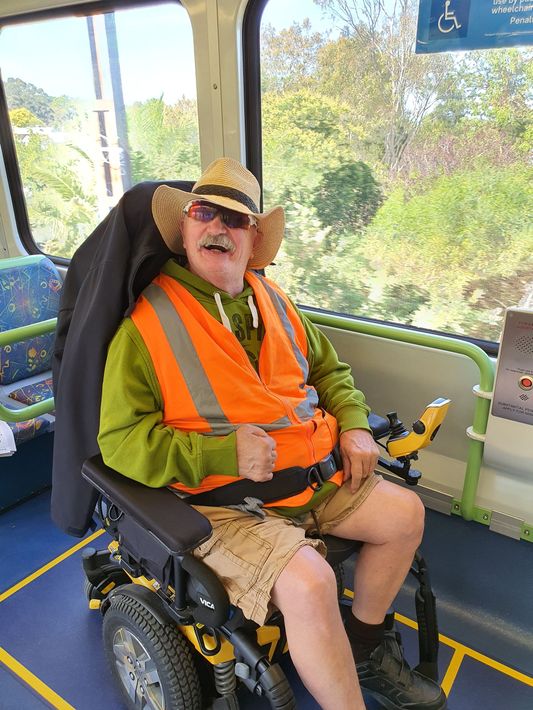 A man in a cowboy hat is sitting in a wheelchair on a bus.