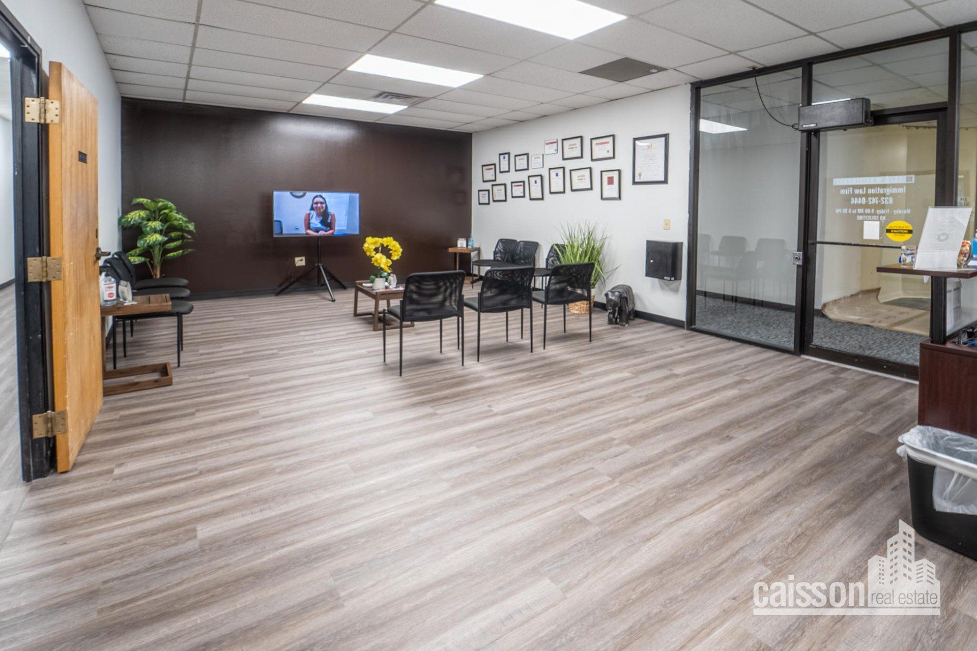 Interior view of suite waiting room with grey flooring, front check-in desk, chairs and tv.