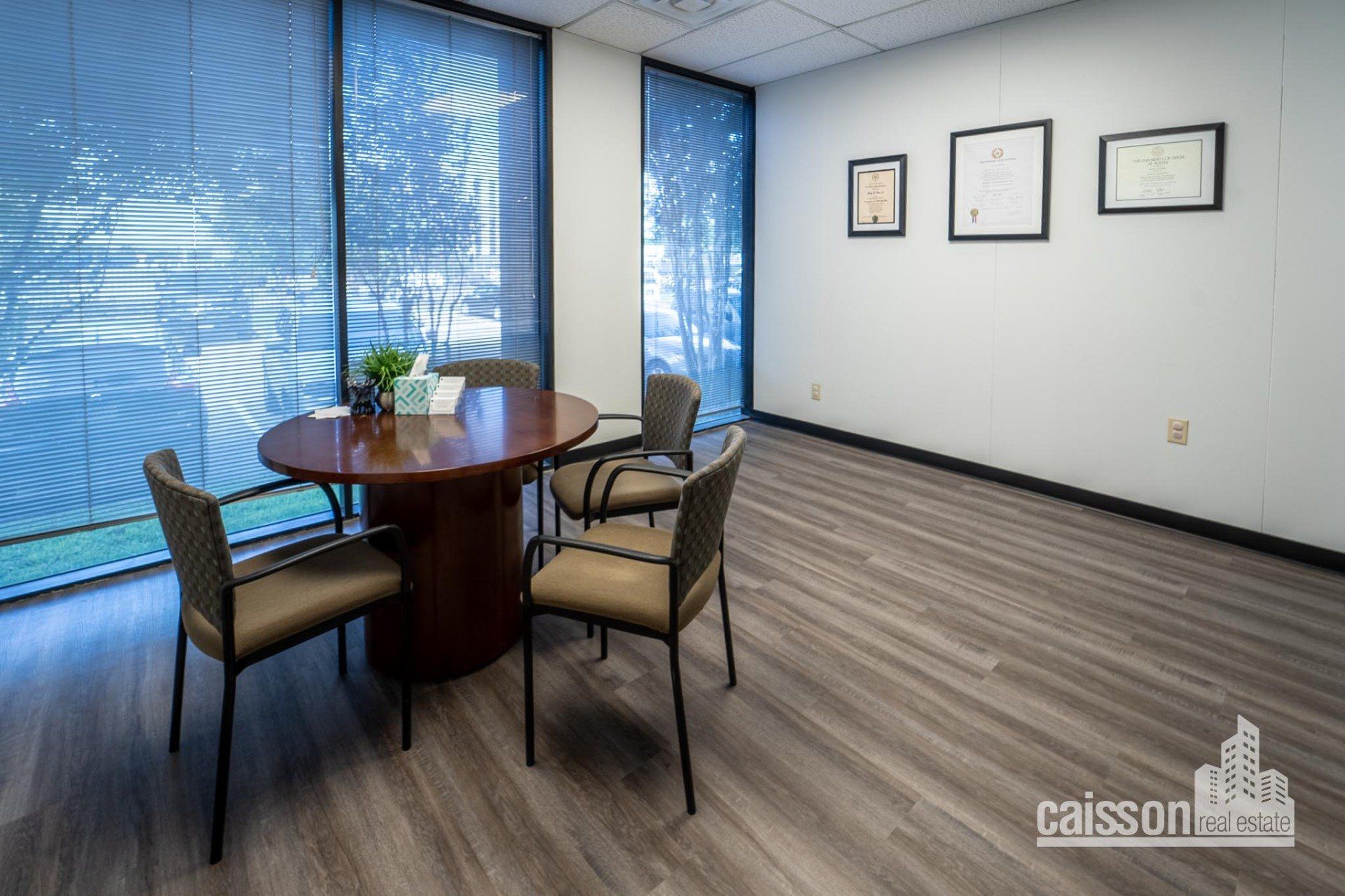 Interior view of suite with grey flooring, round table with chairs near large windows.