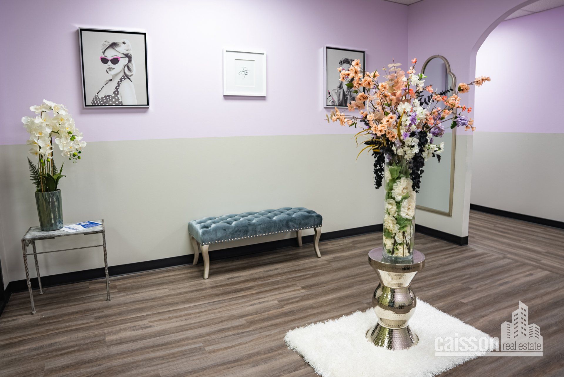 Interior view of lobby of a suite with grey flooring, blue bench, and flowers on table.