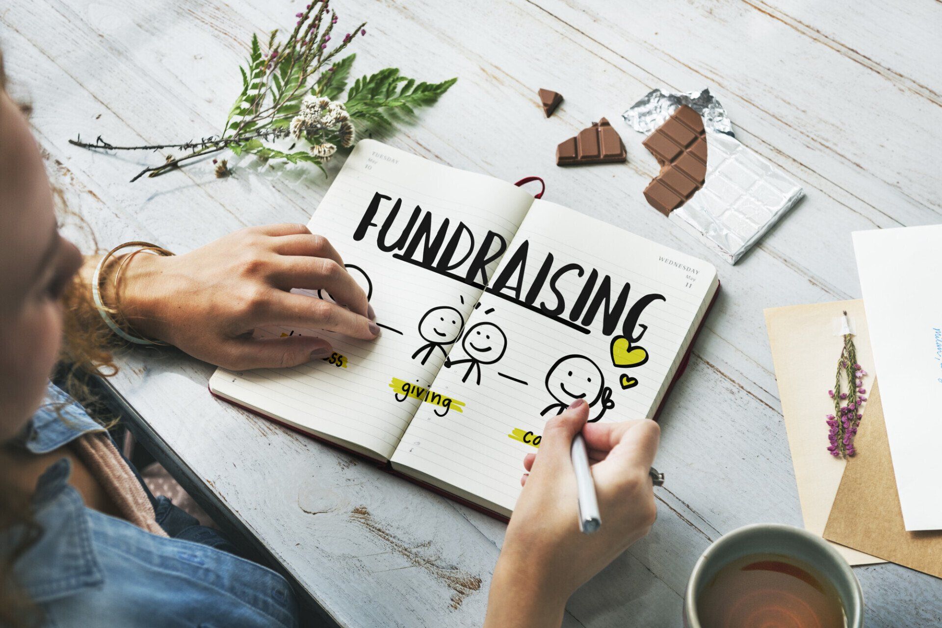 A girl is illustrating on a notebook the definition of fundraising