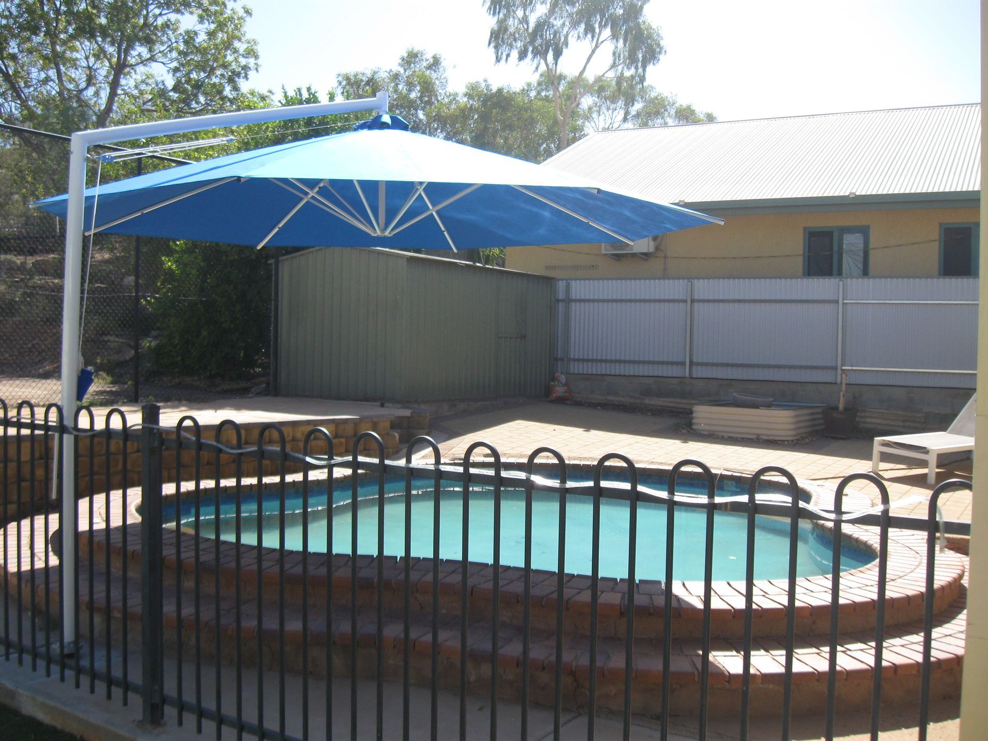 A Blue Umbrella Over A Swimming Pool — Shadetech in Alice in Ciccone, NT