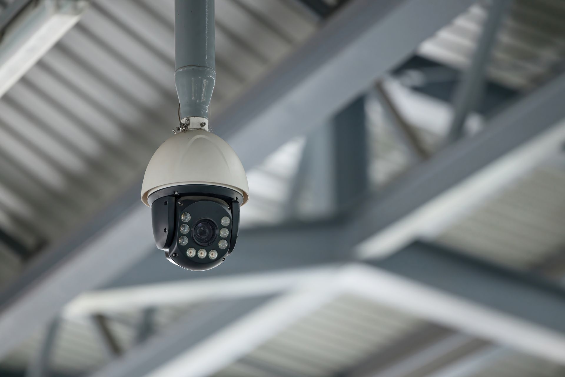 Close-up of a white security camera mounted on a pole. Close-up of a white security camera mounted on a pole.