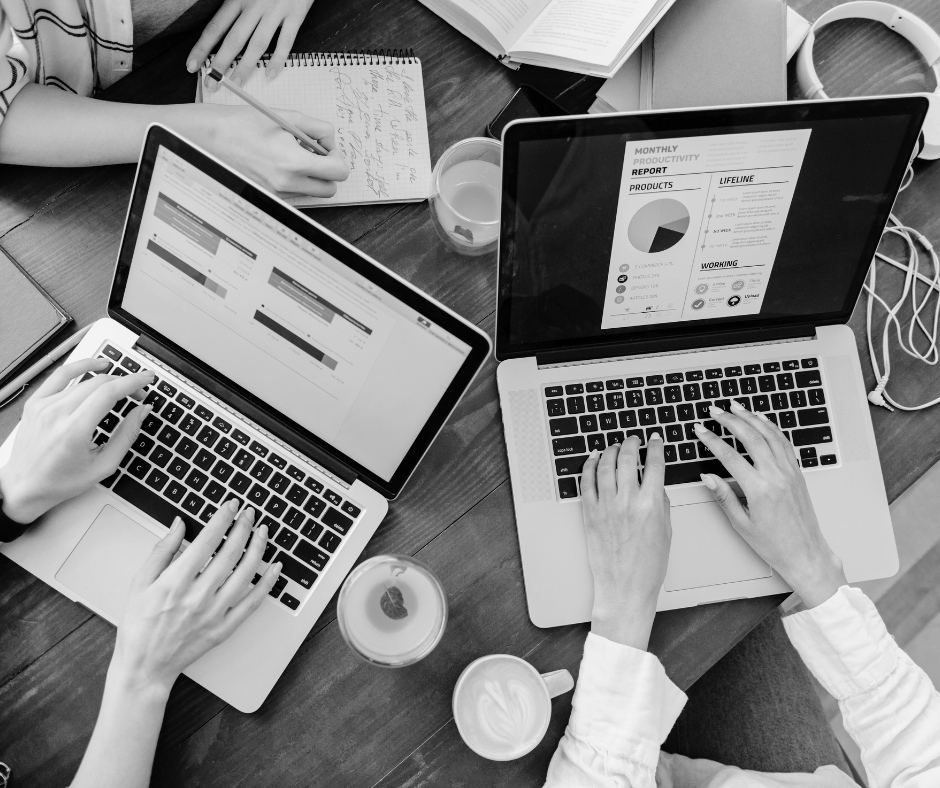 A group of people are sitting at a table using laptops