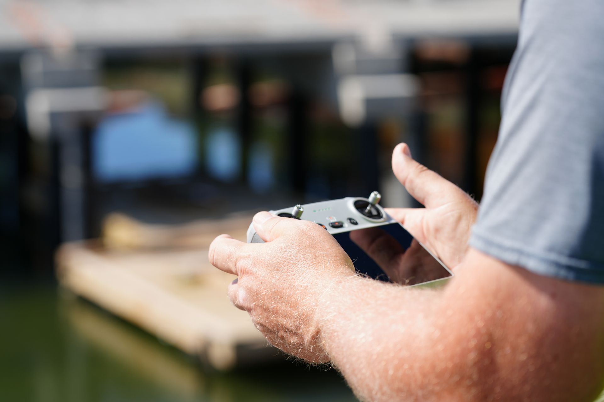 Person holding a drone controller with a blurred industrial background.