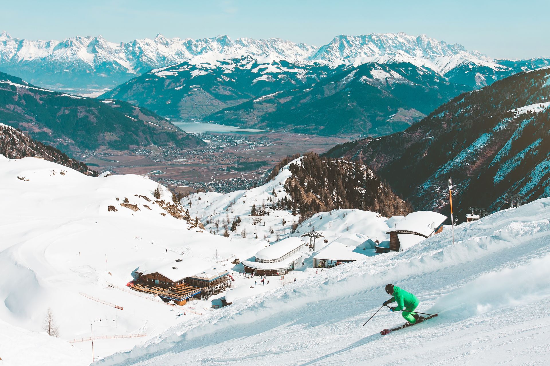 A person is skiing down a snow covered slope with mountains in the background.