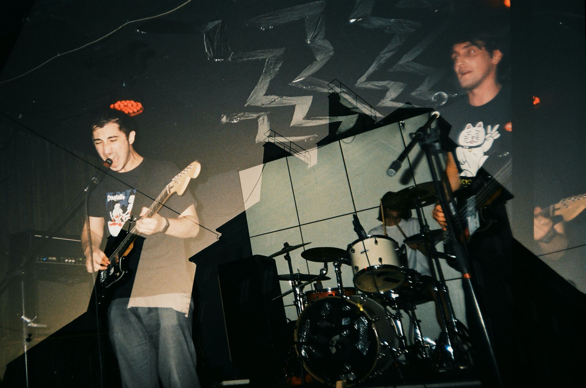 A man playing a guitar in front of a drum set