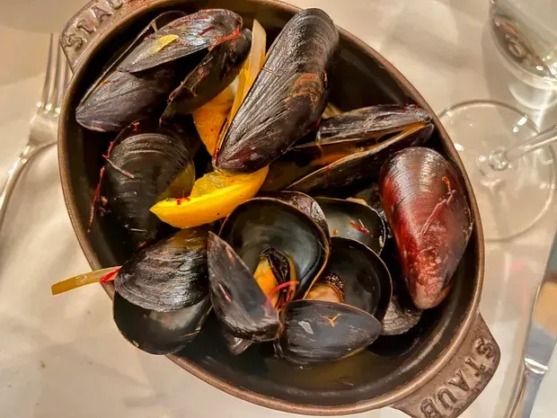 A bowl of mussels is sitting on a table next to a glass of wine.