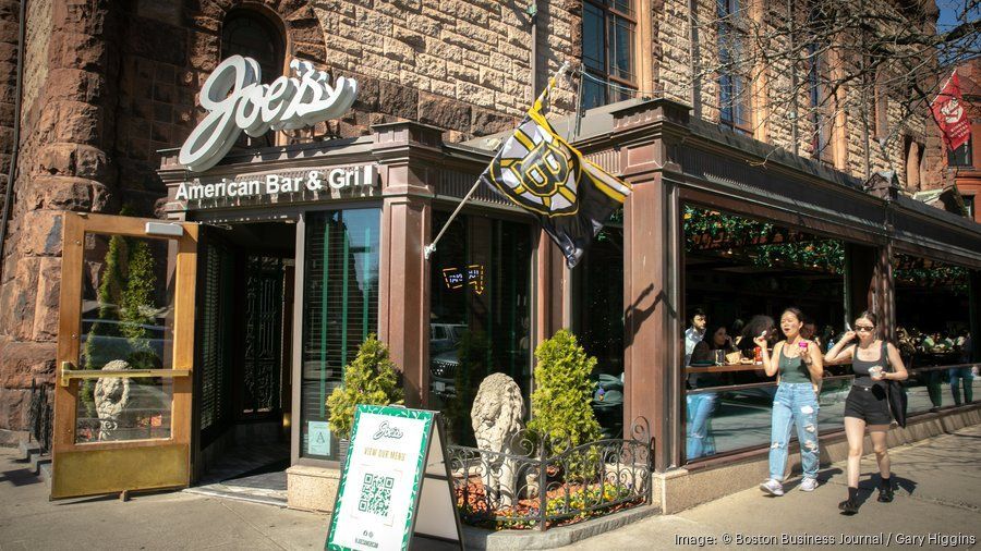 A group of people are walking in front of a joe 's restaurant.