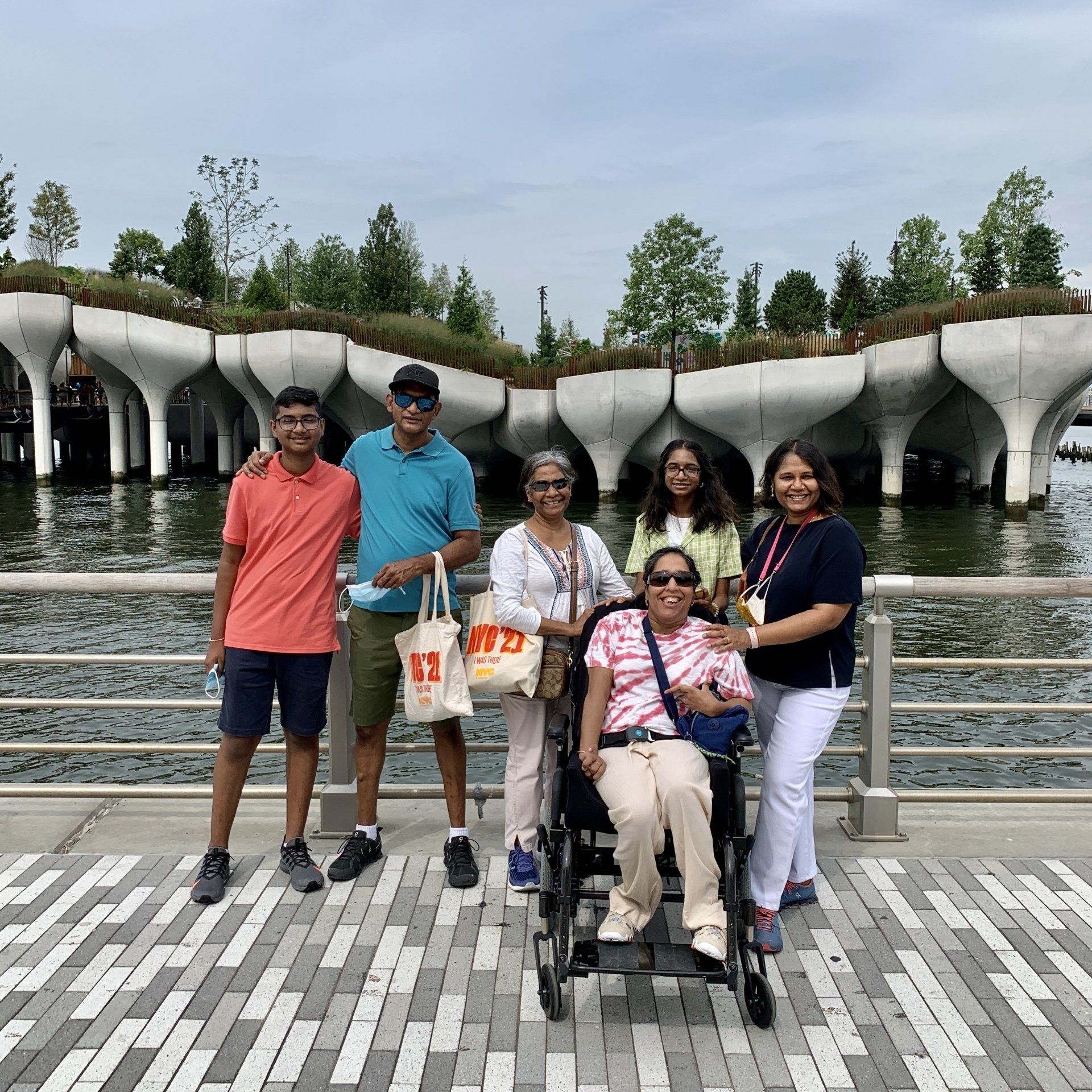 A family photo of all six of us (a brown family) standing in front of Little Island smiling for the camera. It was a cloudy, humid day so the photo is a bit on the grayish side of color.Wheelchair Accessible Travel NYC
