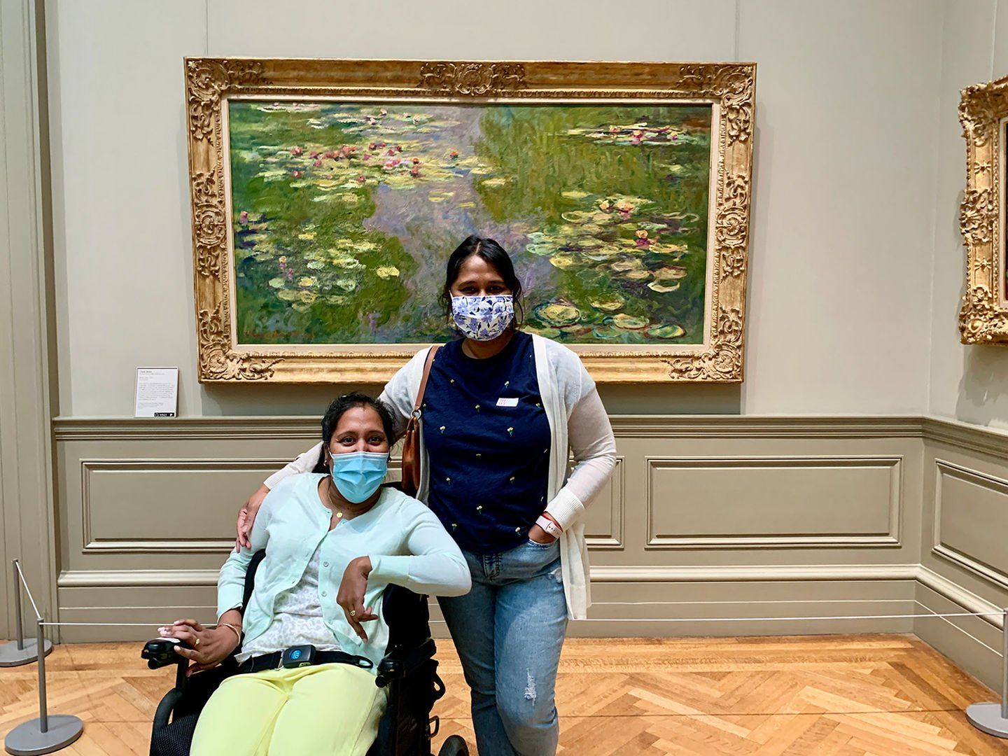 Annie and I are standing facing the camera and clearly smiling behind our masks.  A large Water Lilies is behind us framed in an elaborate gold framing.
