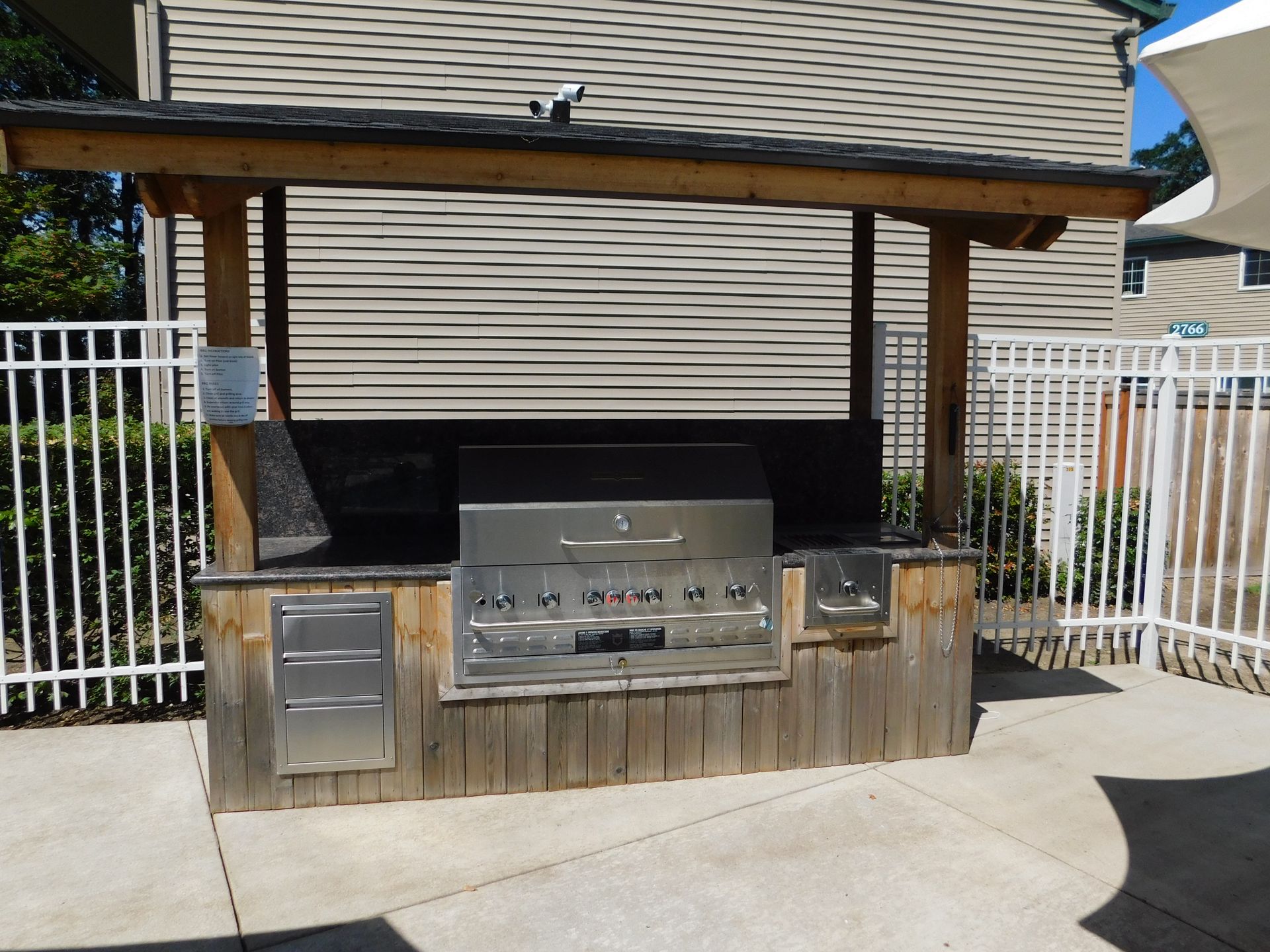 Outdoor grilling station with a covered roof and stainless steel grill.
