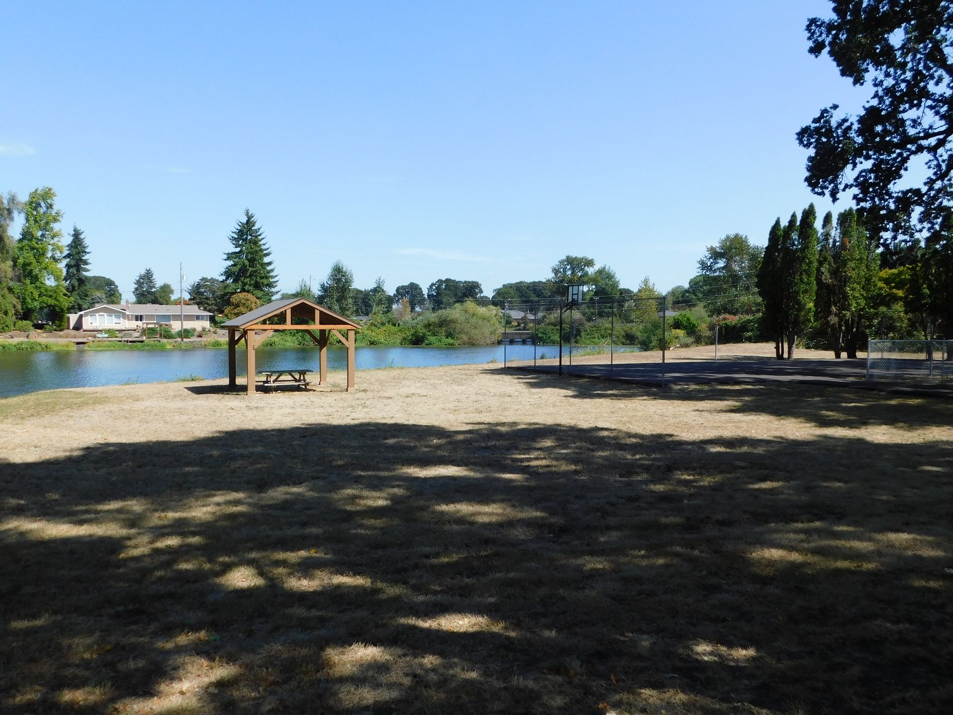 Sandy beach with a gazebo and lake under a clear blue sky.