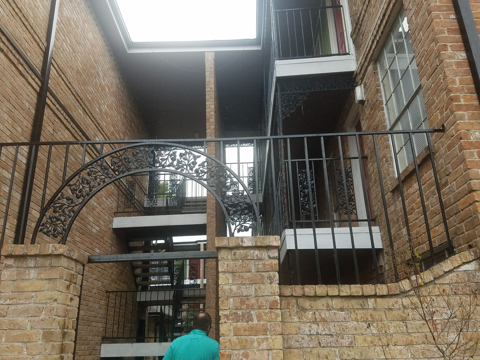 A man in a green shirt is walking up the stairs of a brick building