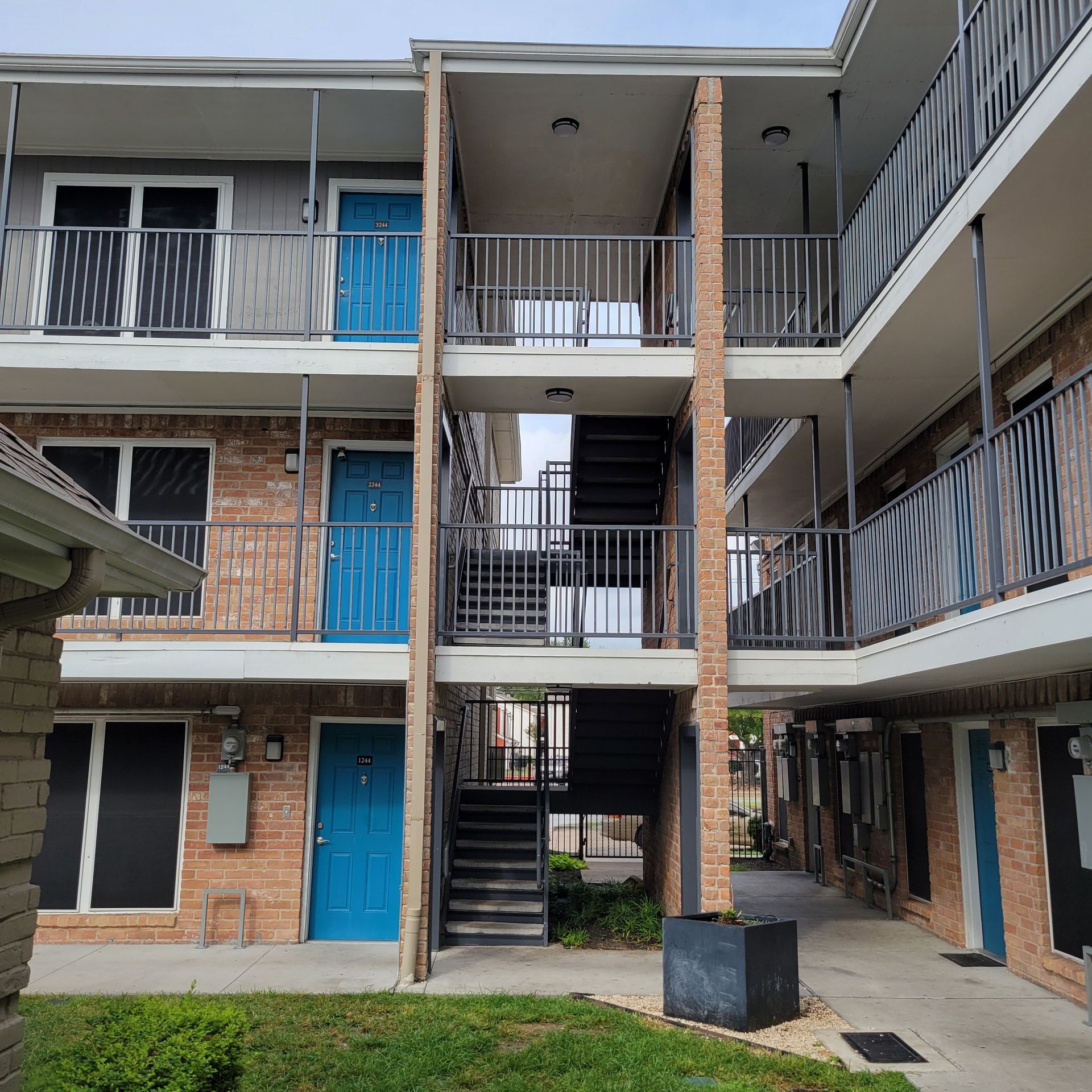 A brick apartment building with blue doors and stairs