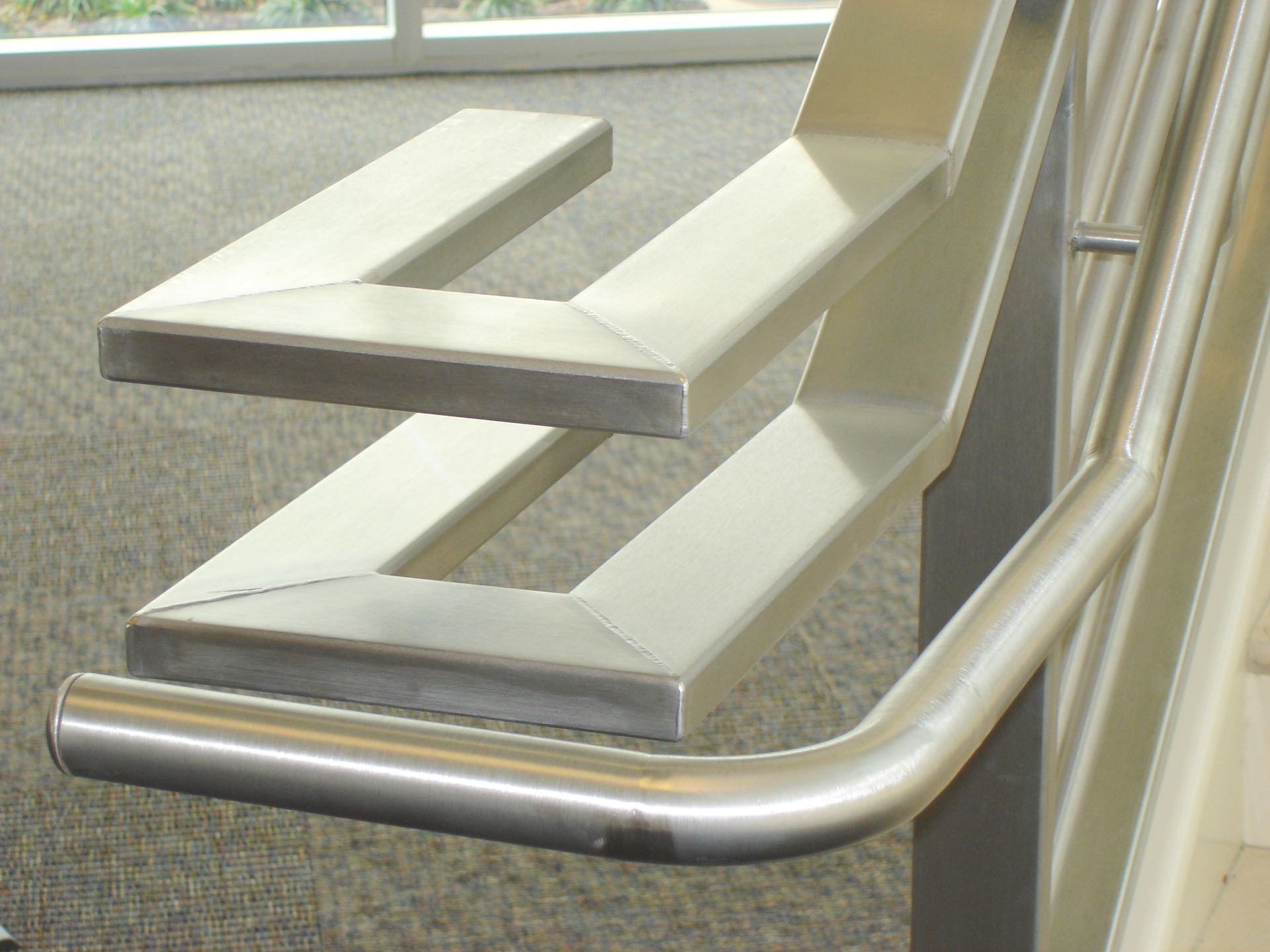 A stainless steel bench with a metal railing