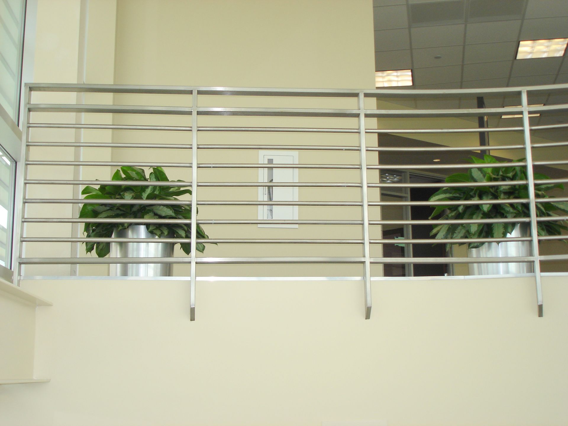 Two potted plants are behind a stainless steel railing