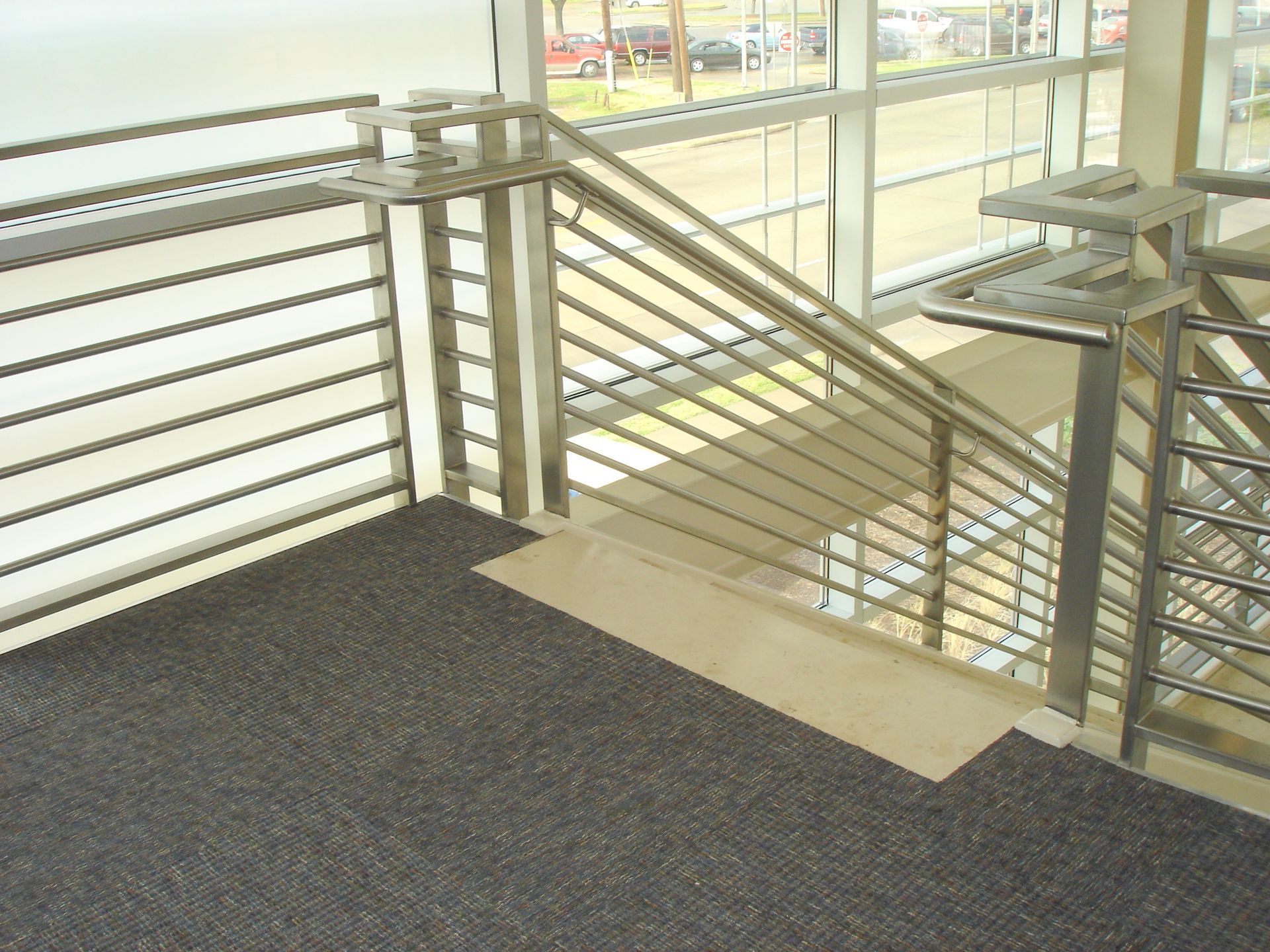 A staircase with a metal railing and a carpeted floor