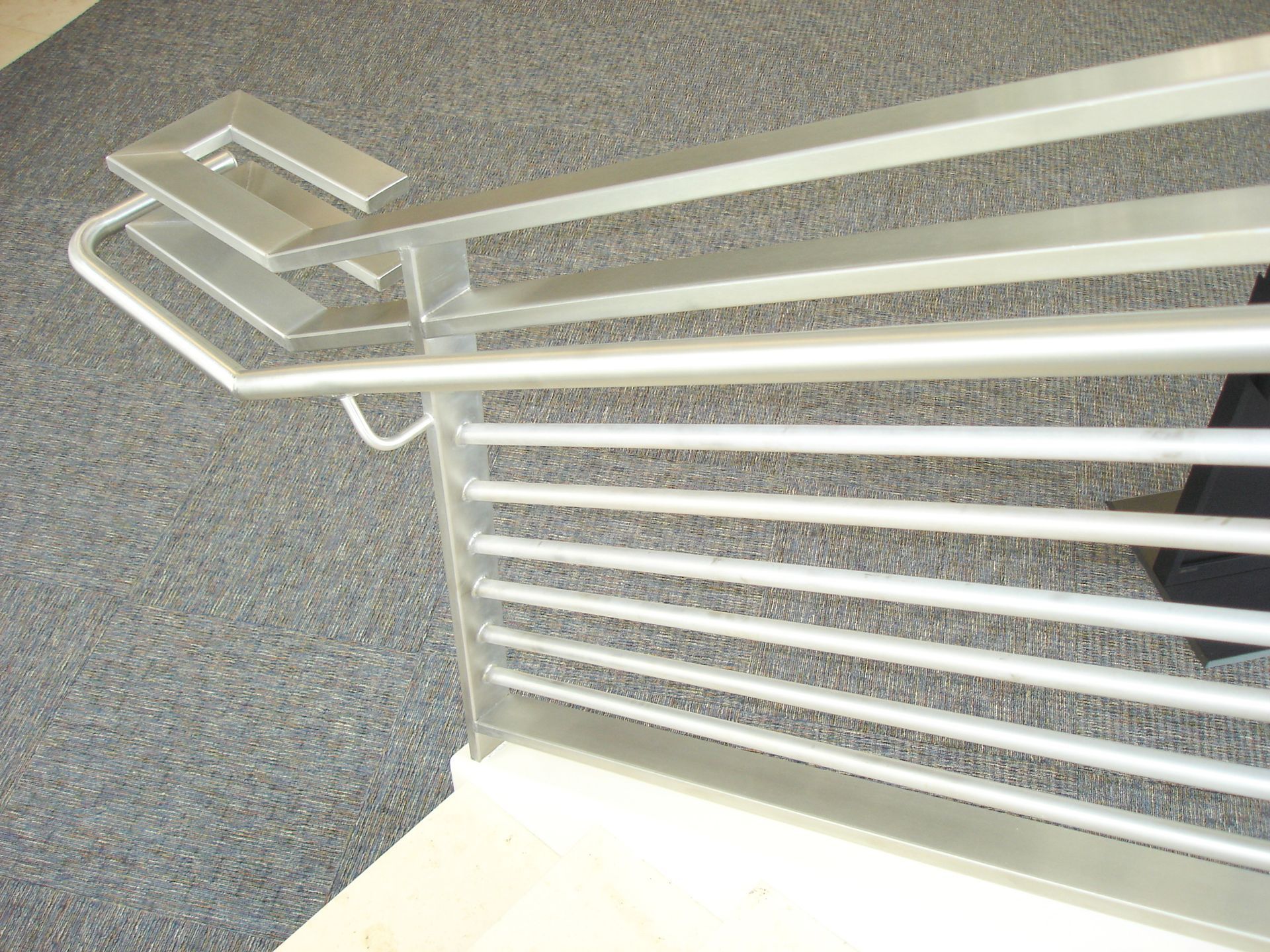 A close up of a metal railing on a carpeted floor